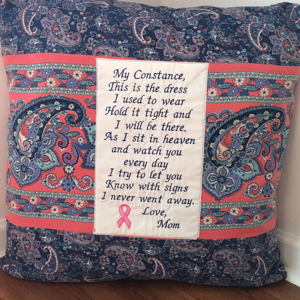 A square decorative throw pillow with a navy blue paisley pattern, coral pink borders, and a central white fabric panel printed with a memorial poem addressed to 'Mom' with a pink ribbon symbol.