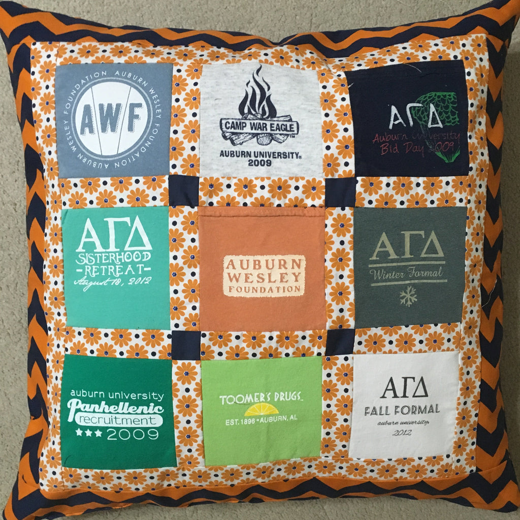 A square decorative throw pillow featuring a 3x3 patchwork design of Auburn University themed T-shirt prints in orange, green, white, and navy, framed by an orange and navy chevron border.